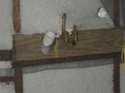 A wooden shelf with two pipes and a cup.