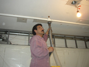 A man is painting the ceiling of his garage.