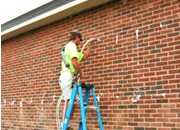 A man on a ladder painting the side of a building.