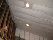 A ceiling with lights and wood beams in the middle.