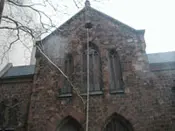 A large brick building with two windows and a tree.