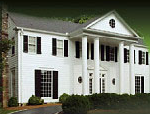 A large white house with columns and black shutters.