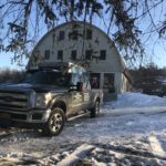 A truck parked in front of a barn.