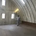 A man standing in an unfinished room with a ladder.